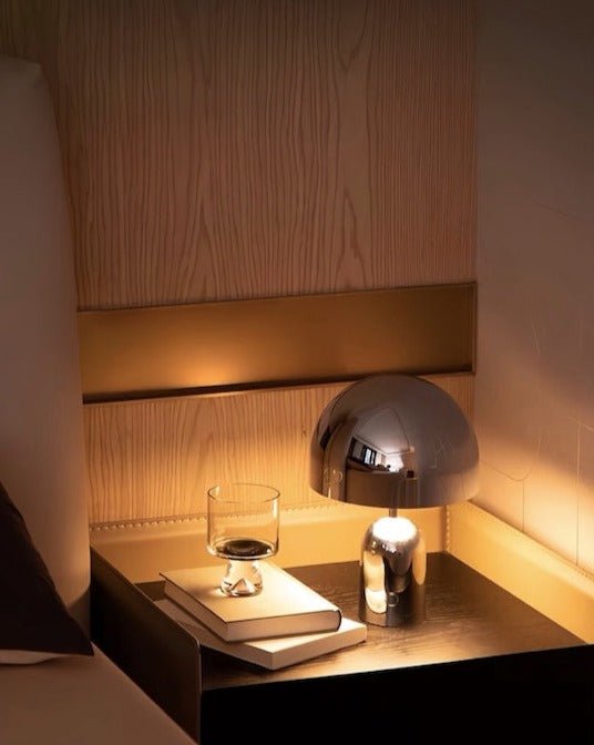 Bell LED Table Lamp with a hyper-polished metallic surface, showcasing a modern design and emitting a warm glow.