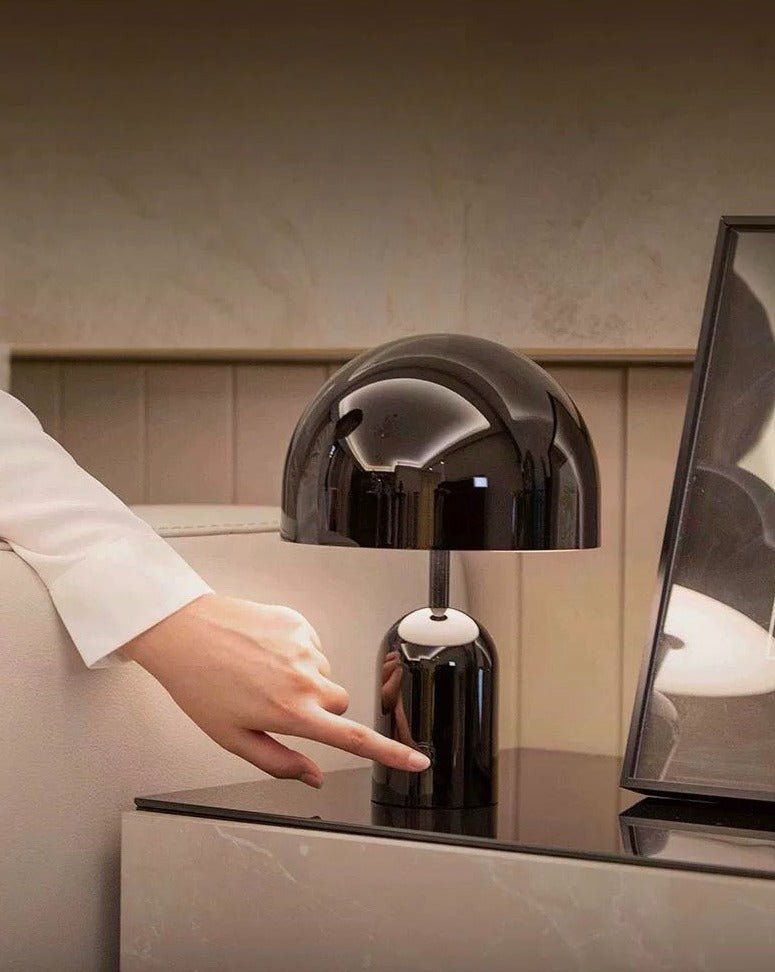 Bell LED Table Lamp with a hyper-polished metallic surface, showcasing a modern design and emitting a warm glow.