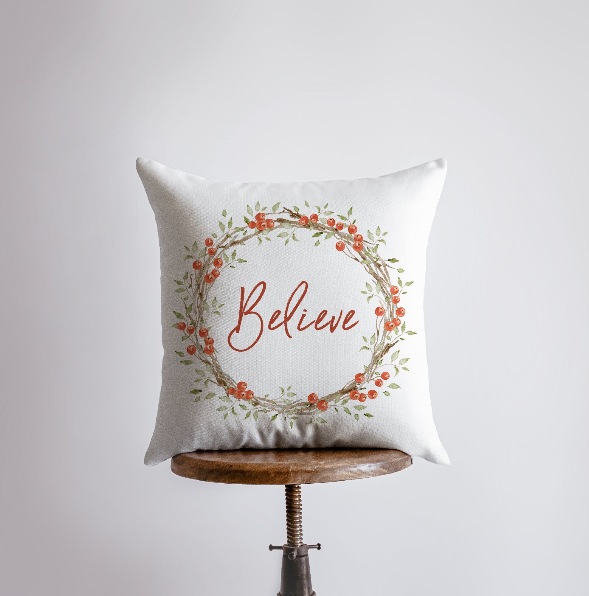Believe with Berry Wreath Christmas Throw Pillow featuring red text and holly berry wreath on a white background, perfect for holiday decor.