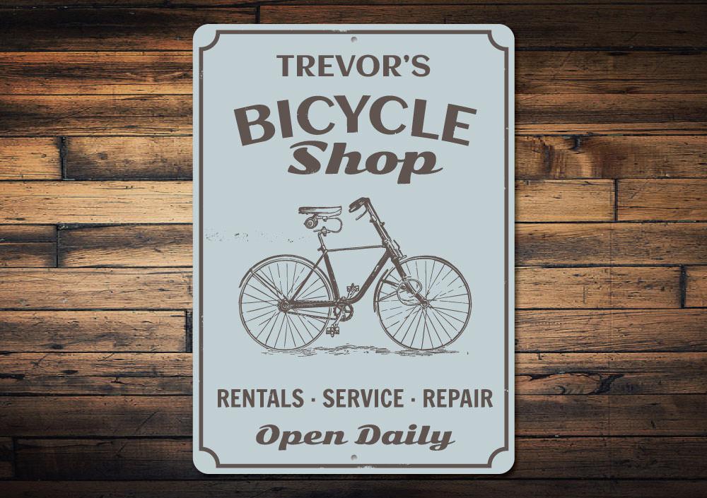A decorative Bicycle Shop Sign made of durable aluminum, featuring customizable text and pre-drilled holes for easy mounting.