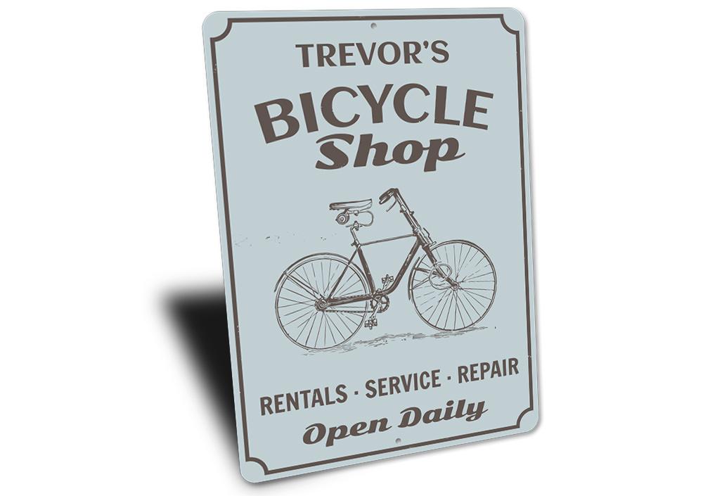 A decorative Bicycle Shop Sign made of durable aluminum, featuring customizable text and pre-drilled holes for easy mounting.