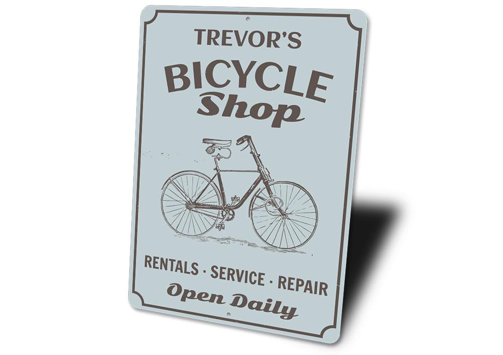 A decorative Bicycle Shop Sign made of durable aluminum, featuring customizable text and pre-drilled holes for easy mounting.