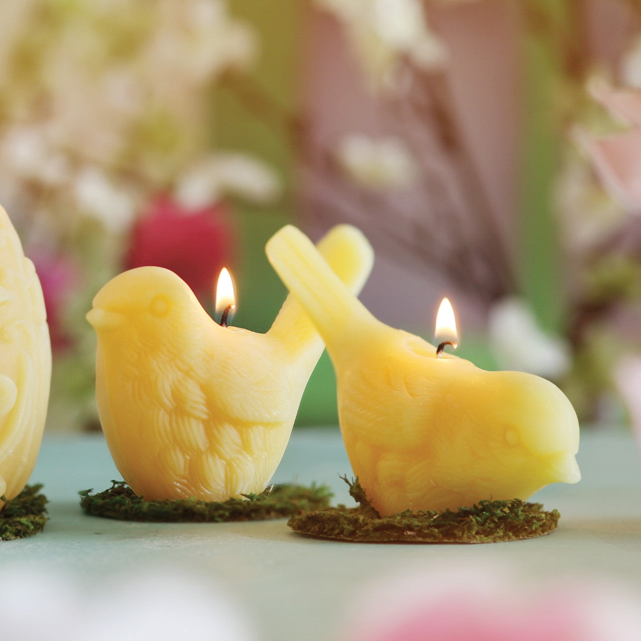 Two handcrafted beeswax song bird candles in upright and pecking positions, showcasing intricate details and natural color.