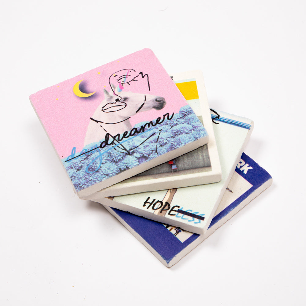 Set von vier Biggdesign Faces Natursteinuntersetzern aus Kalkstein mit bunten Designs und Korkbasis.