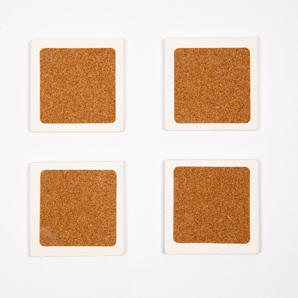 Set von vier Biggdesign Faces Natursteinuntersetzern aus Kalkstein mit bunten Designs und Korkbasis.