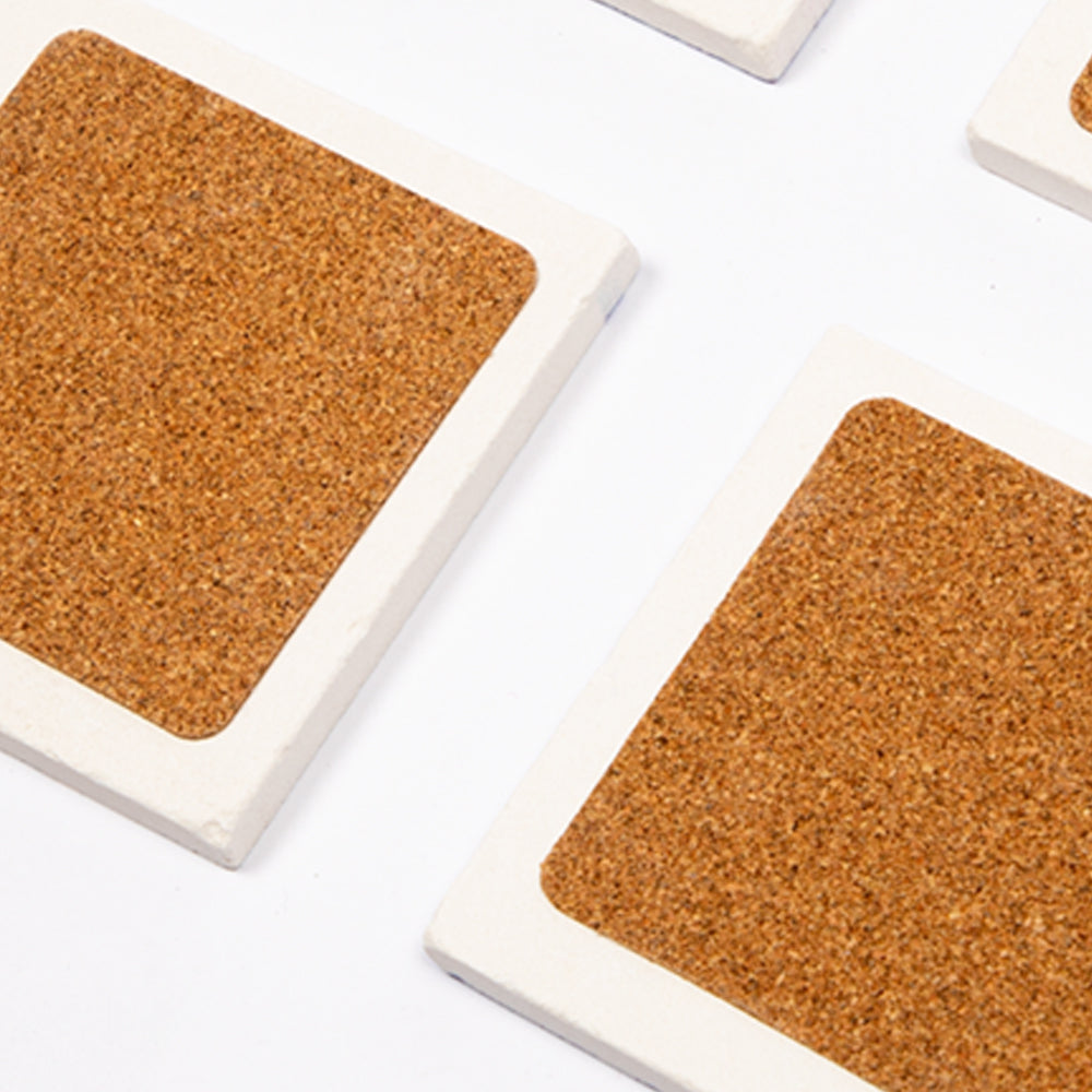 Set von vier Biggdesign Faces Natursteinuntersetzern aus Kalkstein mit bunten Designs und Korkbasis.