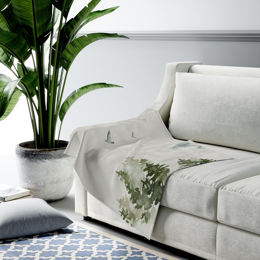 A plush throw blanket featuring a beautiful birds over forest design, showcasing vibrant colors and soft velveteen texture, perfect for cozying up at home.
