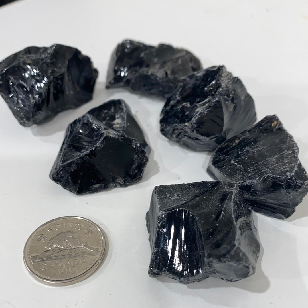 A rough cut piece of Black Obsidian showcasing its glossy black surface and natural edges, symbolizing spiritual protection and emotional healing.
