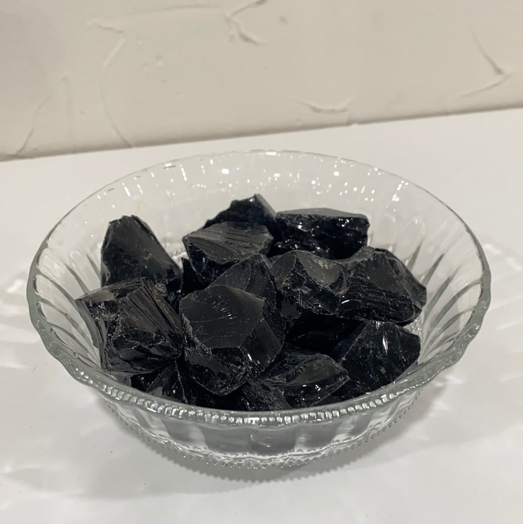 A rough cut piece of Black Obsidian showcasing its glossy black surface and natural edges, symbolizing spiritual protection and emotional healing.