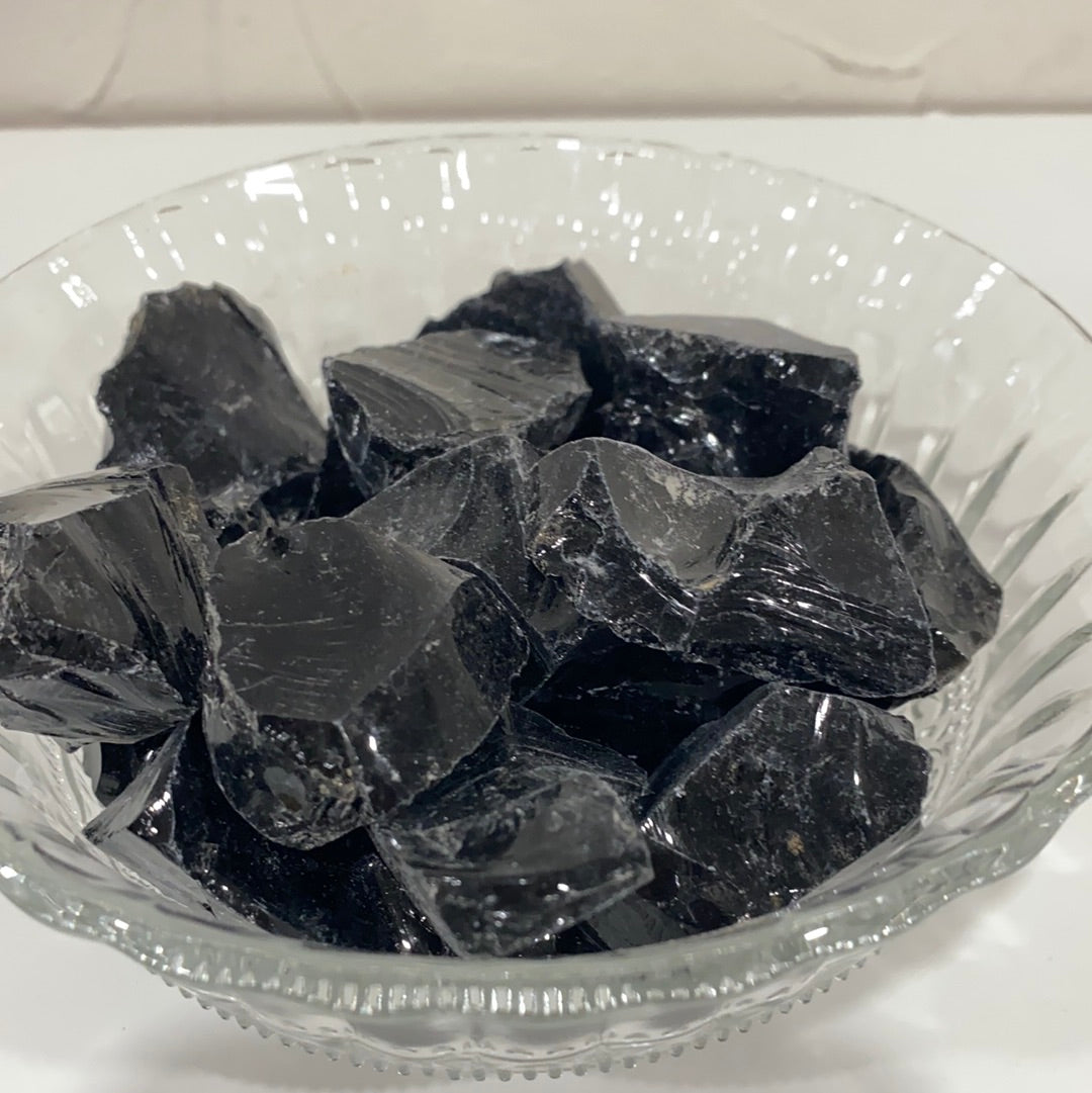 A rough cut piece of Black Obsidian showcasing its glossy black surface and natural edges, symbolizing spiritual protection and emotional healing.