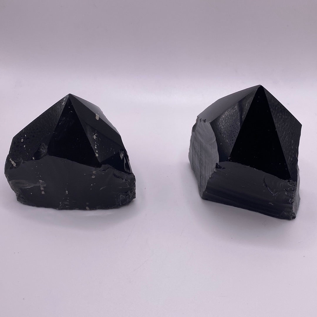 A collection of Black Obsidian Top Polished Rough Cut Towers showcasing their unique shapes and polished surfaces, reflecting light beautifully.