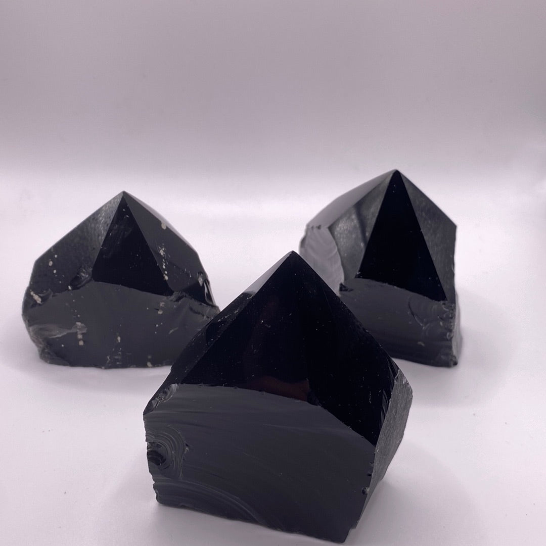A collection of Black Obsidian Top Polished Rough Cut Towers showcasing their unique shapes and polished surfaces, reflecting light beautifully.
