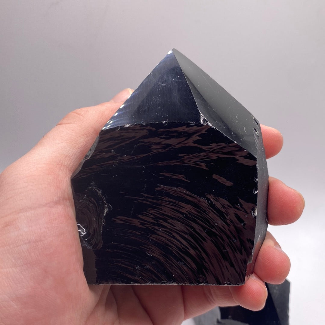 A collection of Black Obsidian Top Polished Rough Cut Towers showcasing their unique shapes and polished surfaces, reflecting light beautifully.