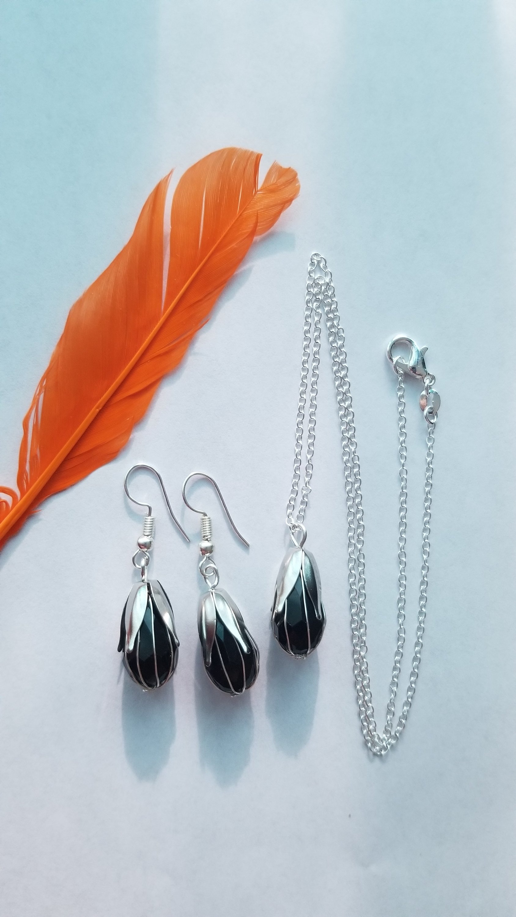 Elegant black pendant with chain and matching earrings, showcasing a translucent design.