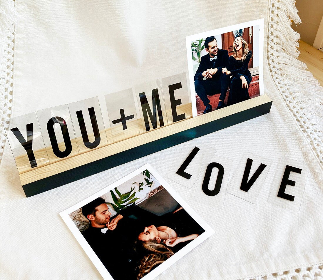 Elegant black wooden photo ledge with mustard accent, displaying various photos and art prints.
