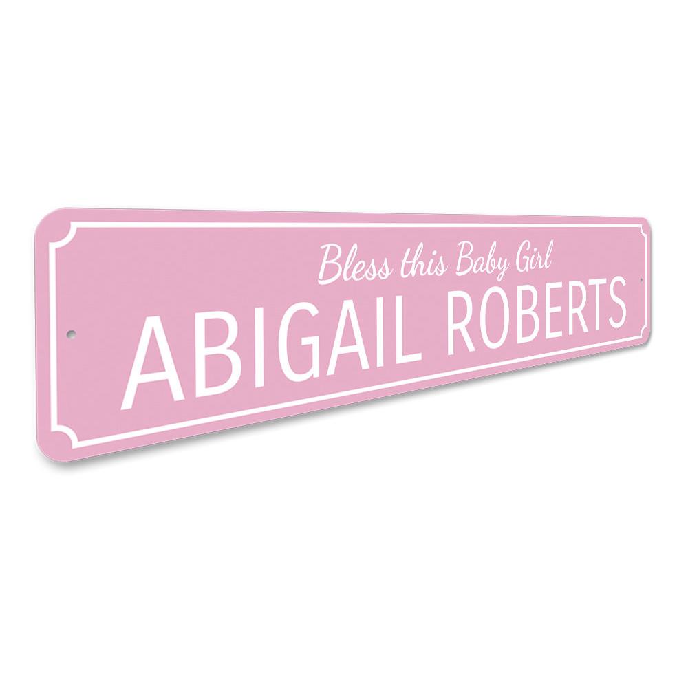 A decorative Bless This Baby Girl Sign made of high-quality aluminum, featuring a charming design suitable for children's rooms.