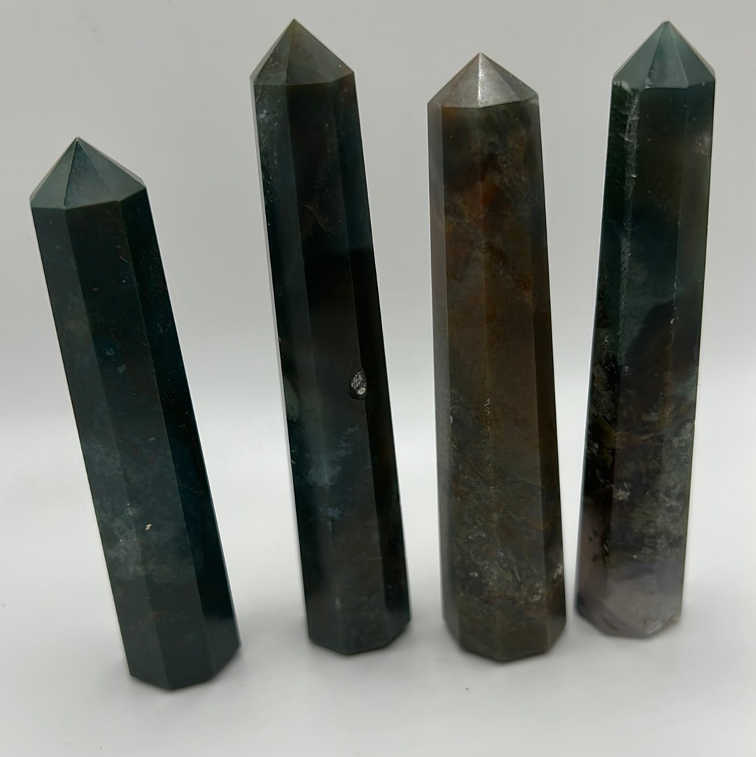 A polished bloodstone point tower, 3-5 inches tall, showcasing deep green hues with red and brown speckles, reflecting light beautifully.