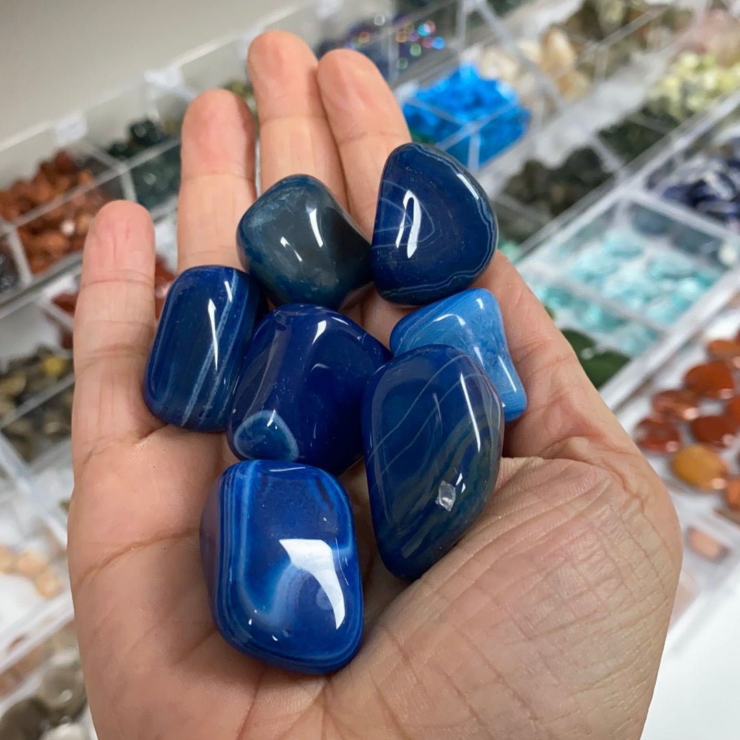 A collection of Blue Agate Dyed Tumbled Stones showcasing vibrant blue hues and unique patterns, perfect for healing and meditation.