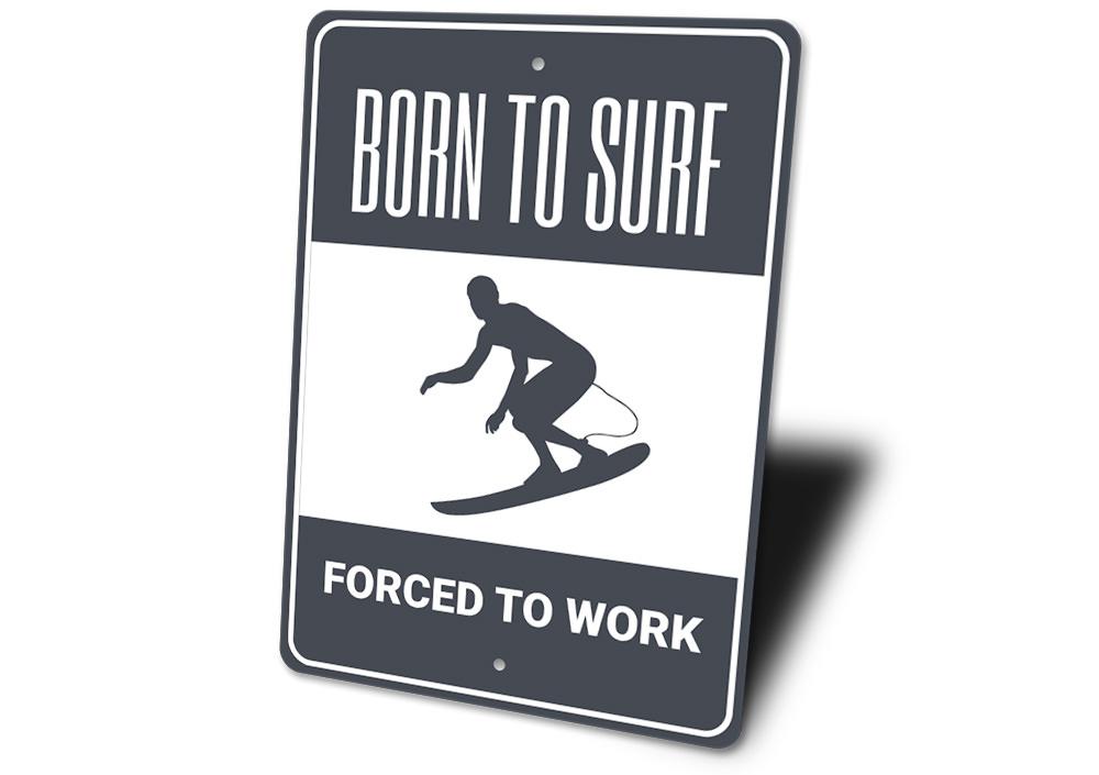 A decorative metal sign reading 'Born to Surf Forced to Work', featuring vibrant colors and a beach-themed design, perfect for coastal decor.