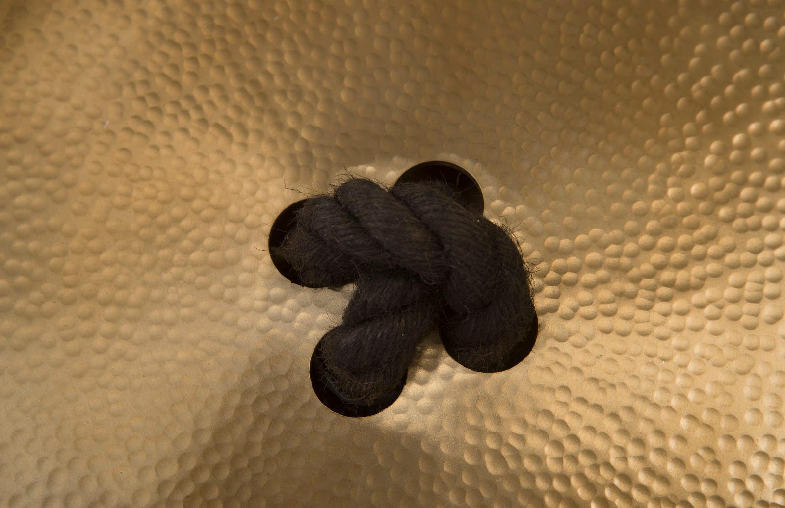 Button Wall Tile featuring a hammered metal design with a brass finish, showcasing its oversized button shape and intricate texture.