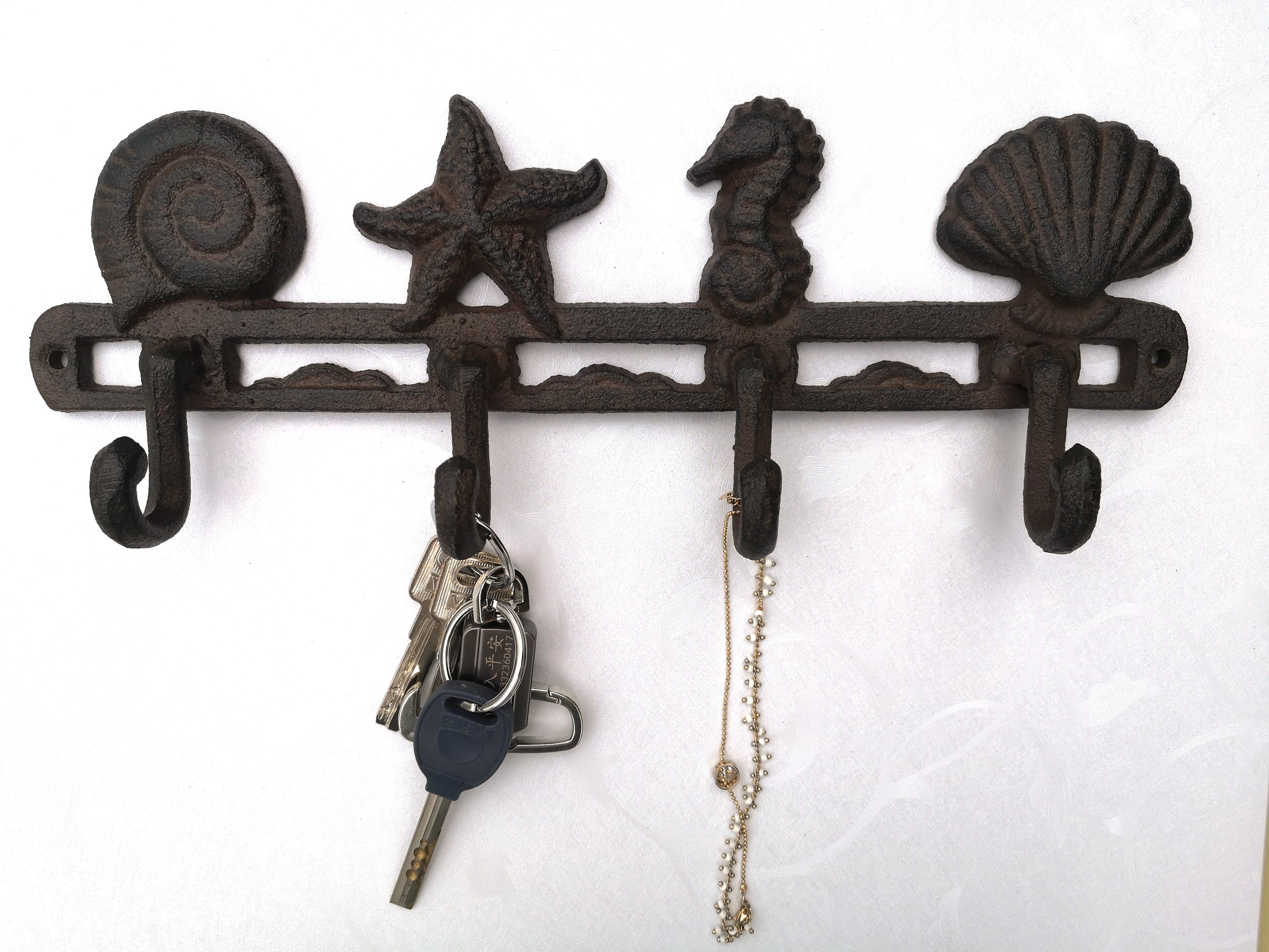 A pair of 13-inch cast iron seashell wall hooks, showcasing intricate detailing and a rustic finish, perfect for beach-themed decor.