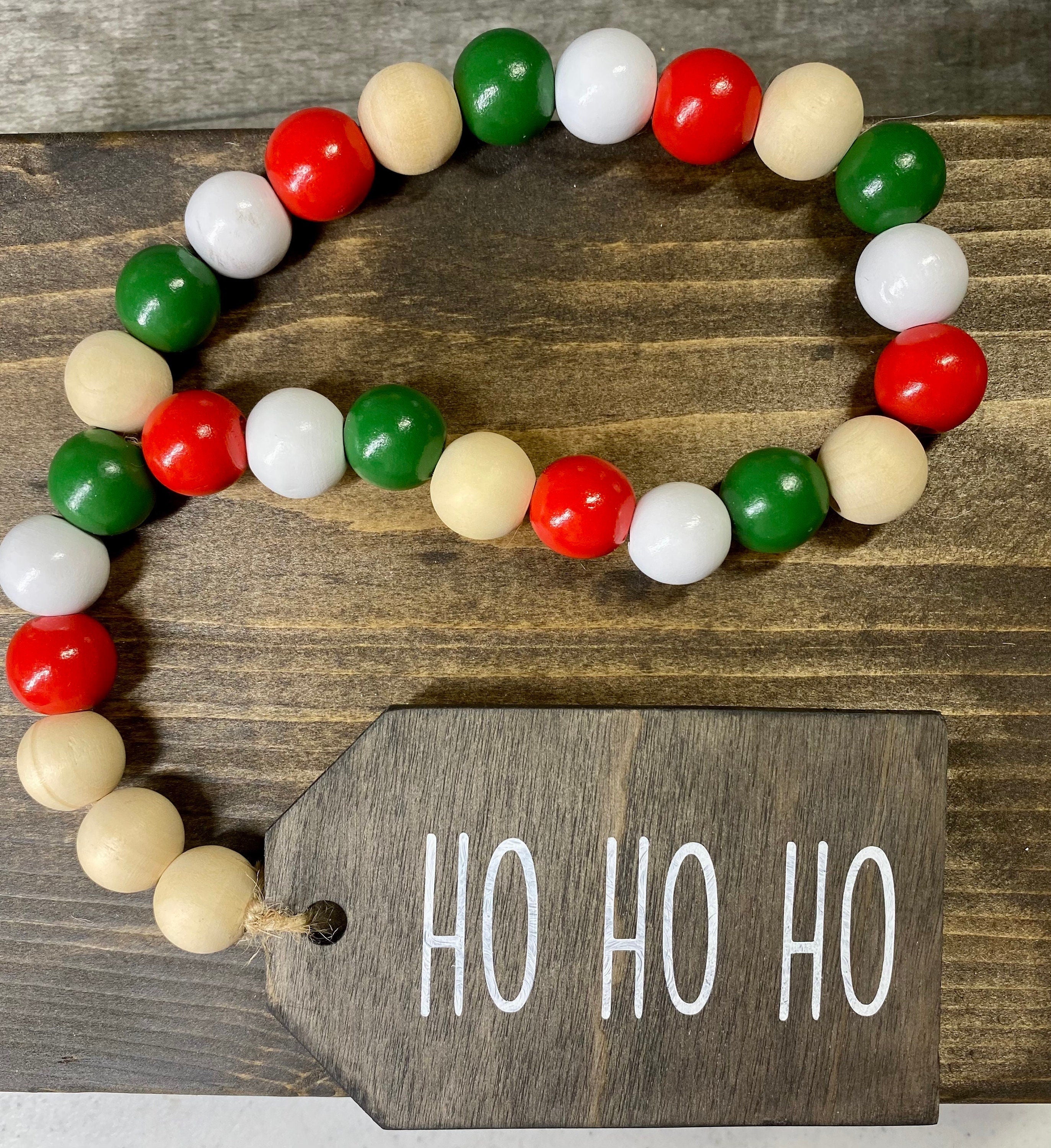 Handmade Christmas beaded looped garland featuring red, green, white, and natural wood beads with a 'Ho Ho Ho' wooden tag.