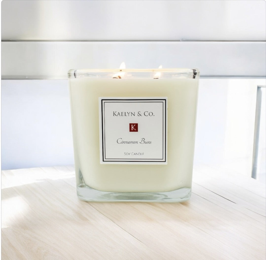 A large cube candle with a cinnamon bun fragrance, featuring a smooth surface and triple wicks, set against a cozy background.