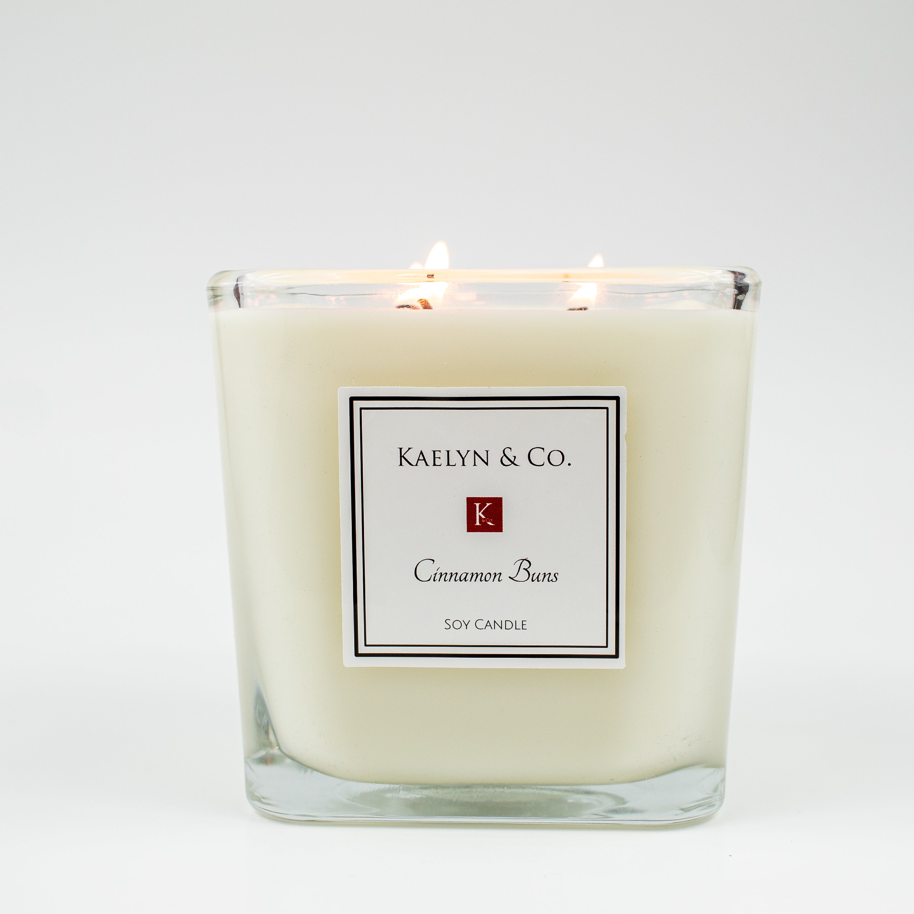 A large cube candle with a cinnamon bun fragrance, featuring a smooth surface and triple wicks, set against a cozy background.
