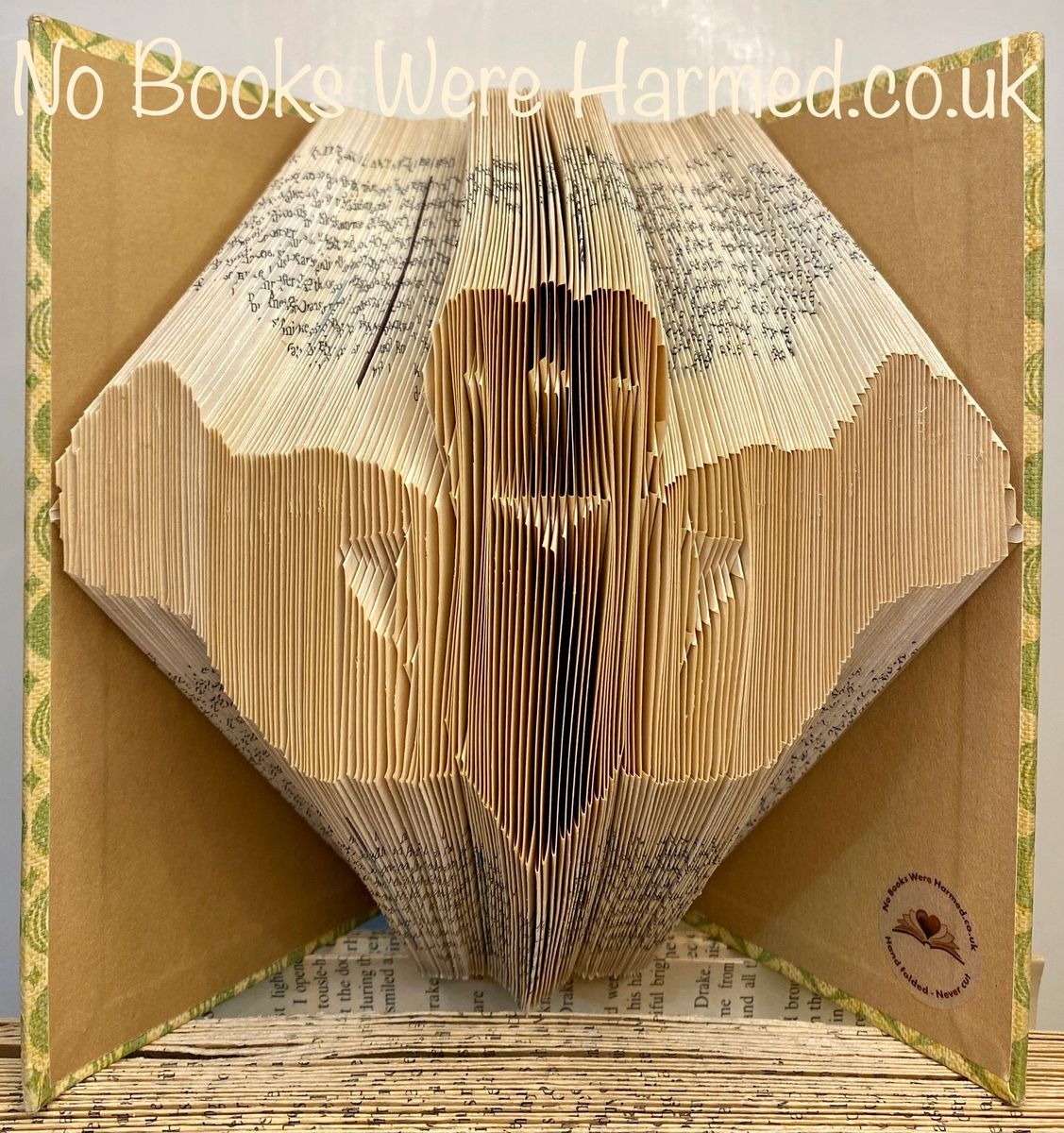 Handcrafted Claddagh art piece made from vintage book pages, showcasing unique colors and intricate folds.