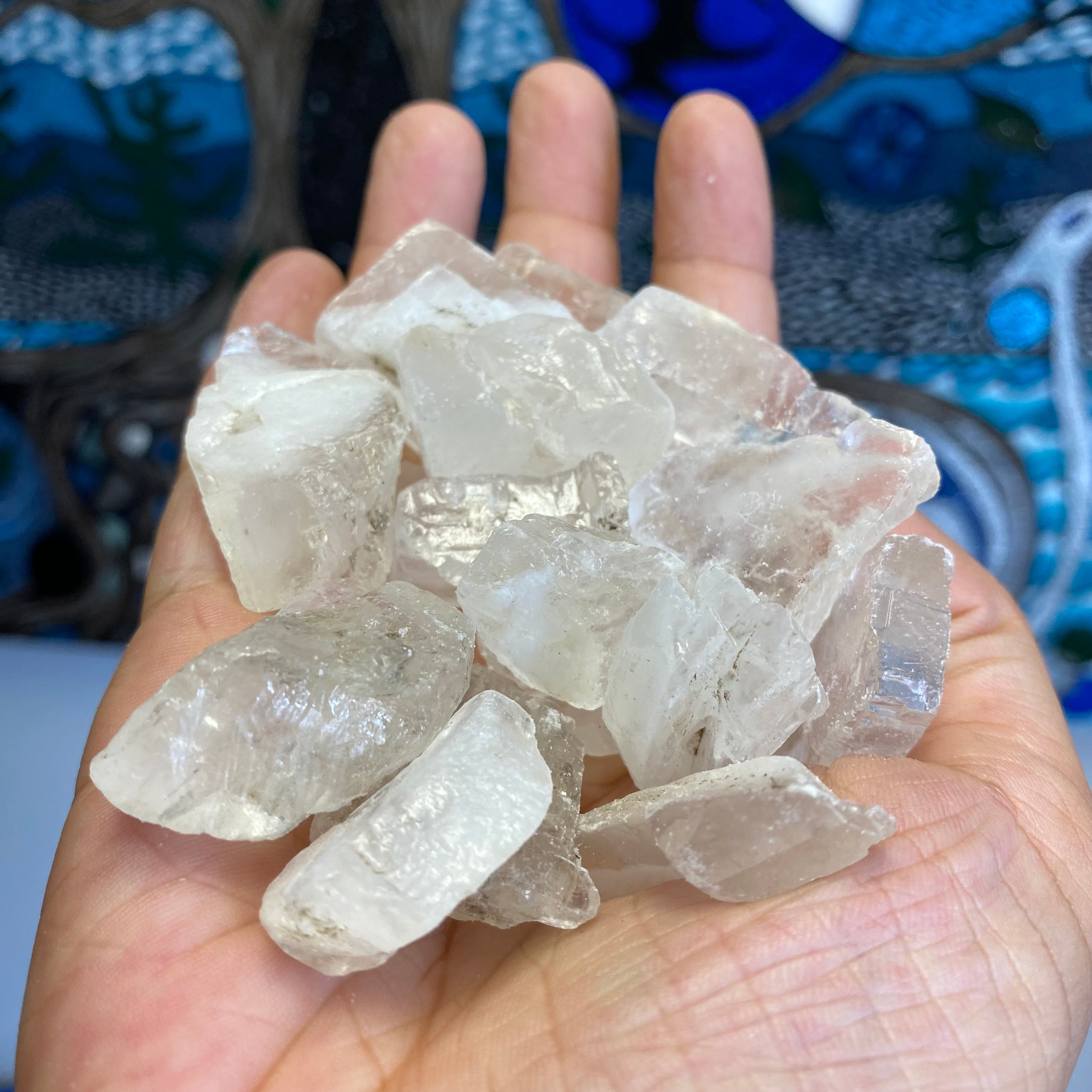A collection of Clear Calcite Natural Rough Cut pieces showcasing various shapes and sizes, ranging from round to flat.