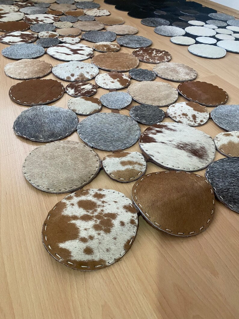A luxurious round patchwork cow skin rug showcasing natural leather textures and patterns, perfect for modern home decor.