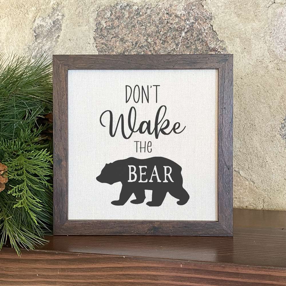 Don't Wake the Bear framed sign with a stylized wood frame, featuring eco-friendly printing on a linen-look background.