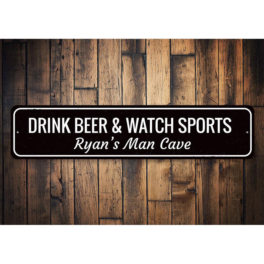 A decorative metal sign that reads 'Drink Beer & Watch Sports', perfect for man caves and game rooms, showcasing quality craftsmanship.