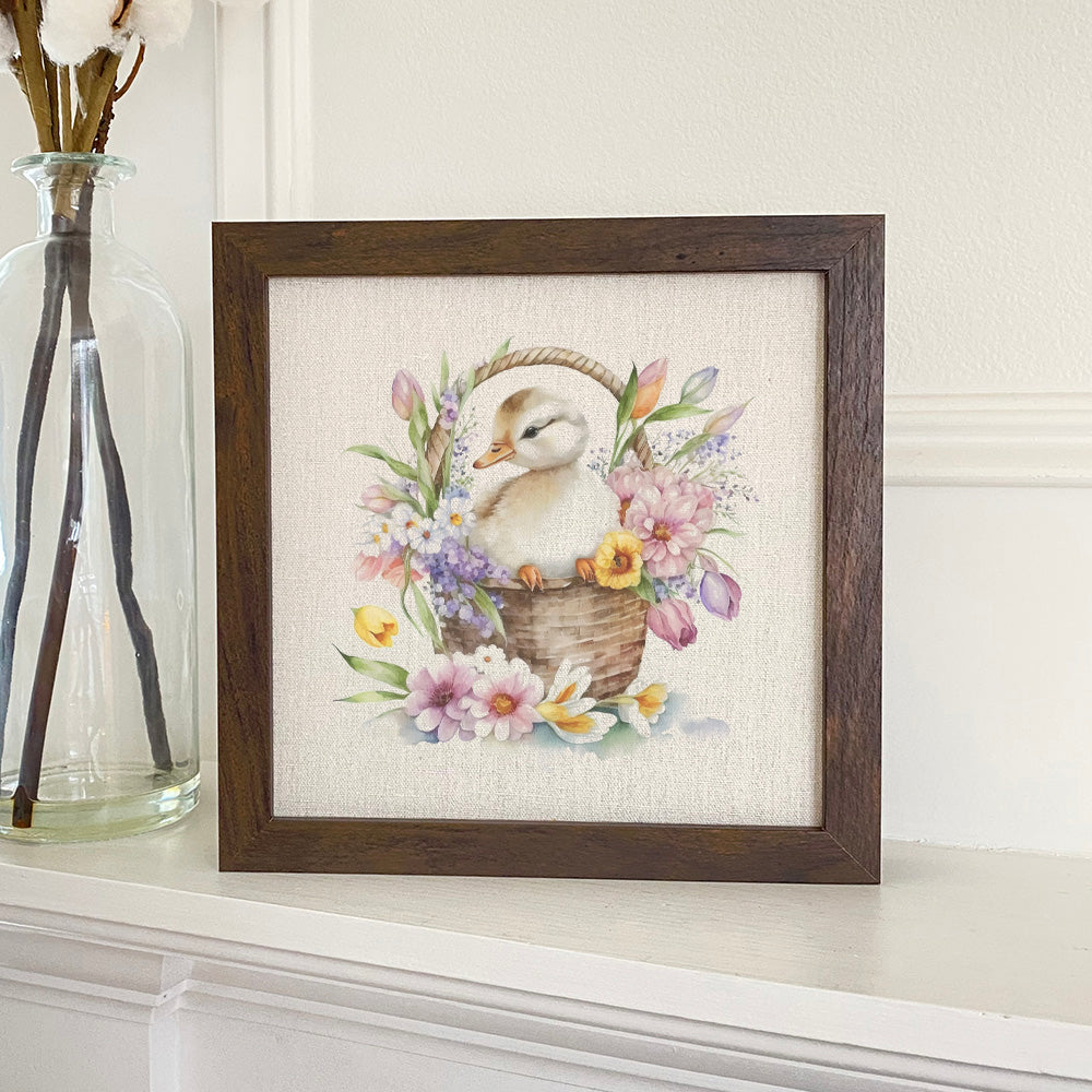 Framed sign featuring a cute duckling in a flower basket, with a stylized wood frame in walnut or white-washed finish.