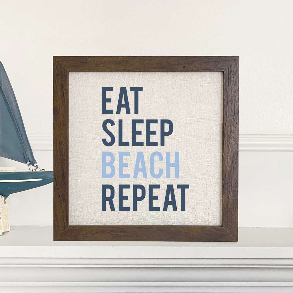 Eat Sleep Beach Repeat framed sign with a natural wood frame and linen-look background, perfect for beach-themed decor.