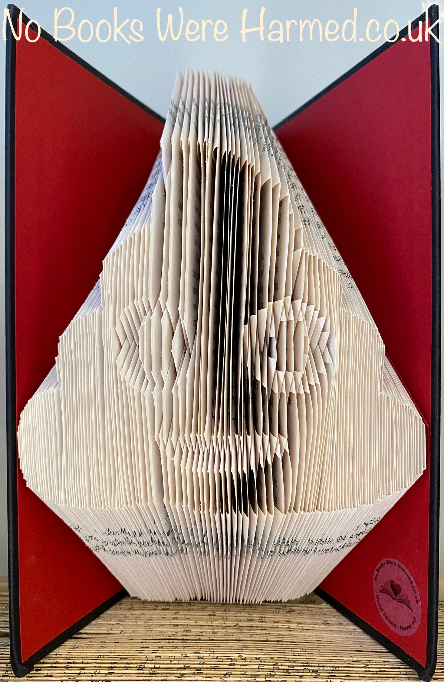 A colorful Emojipoo art piece made from hand-folded pages of vintage books, showcasing intricate designs and unique patterns.