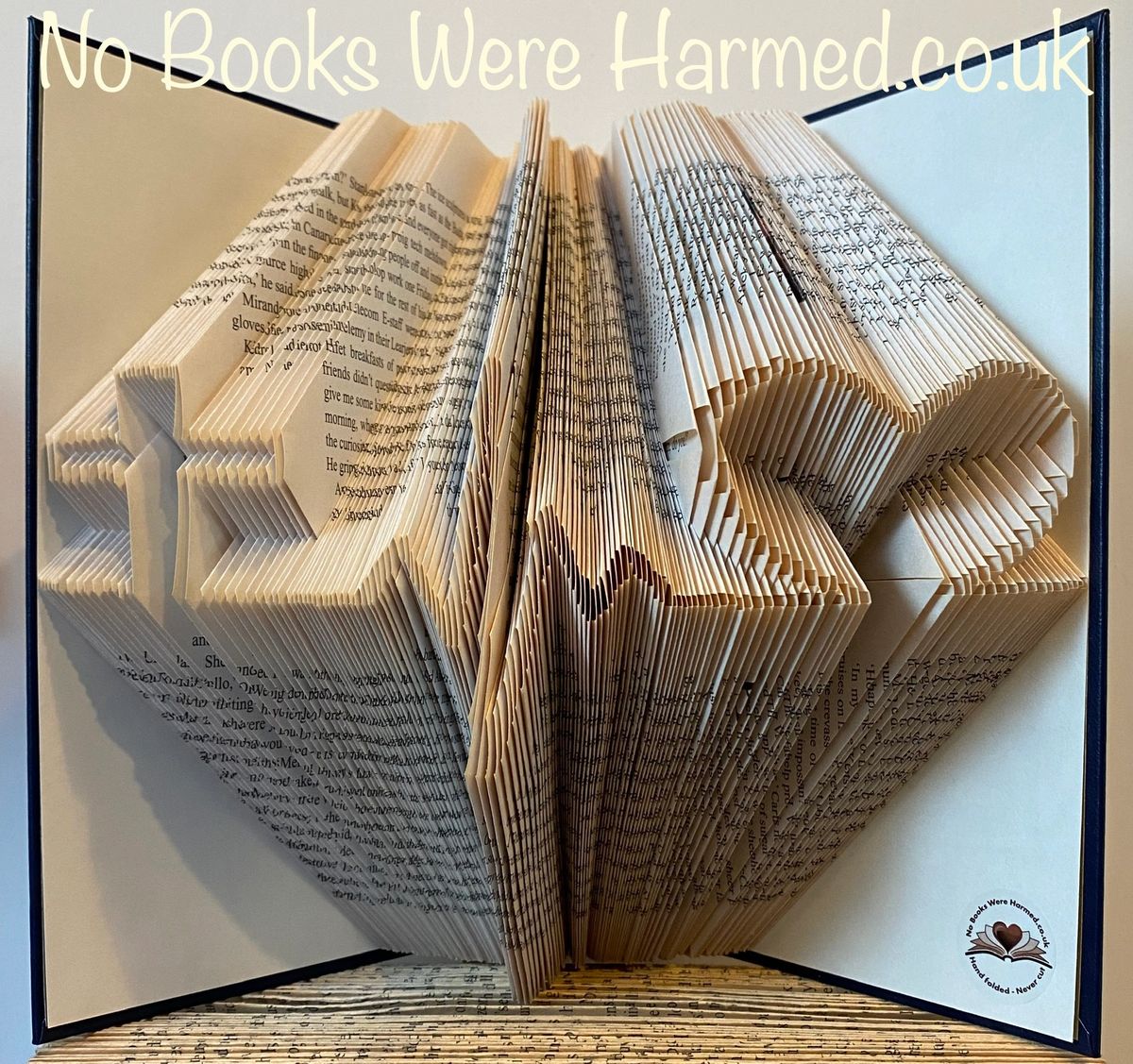 Hand folded book art featuring a cross, heartbeat, and heart symbolizing faith, life, and love, crafted from vintage books.
