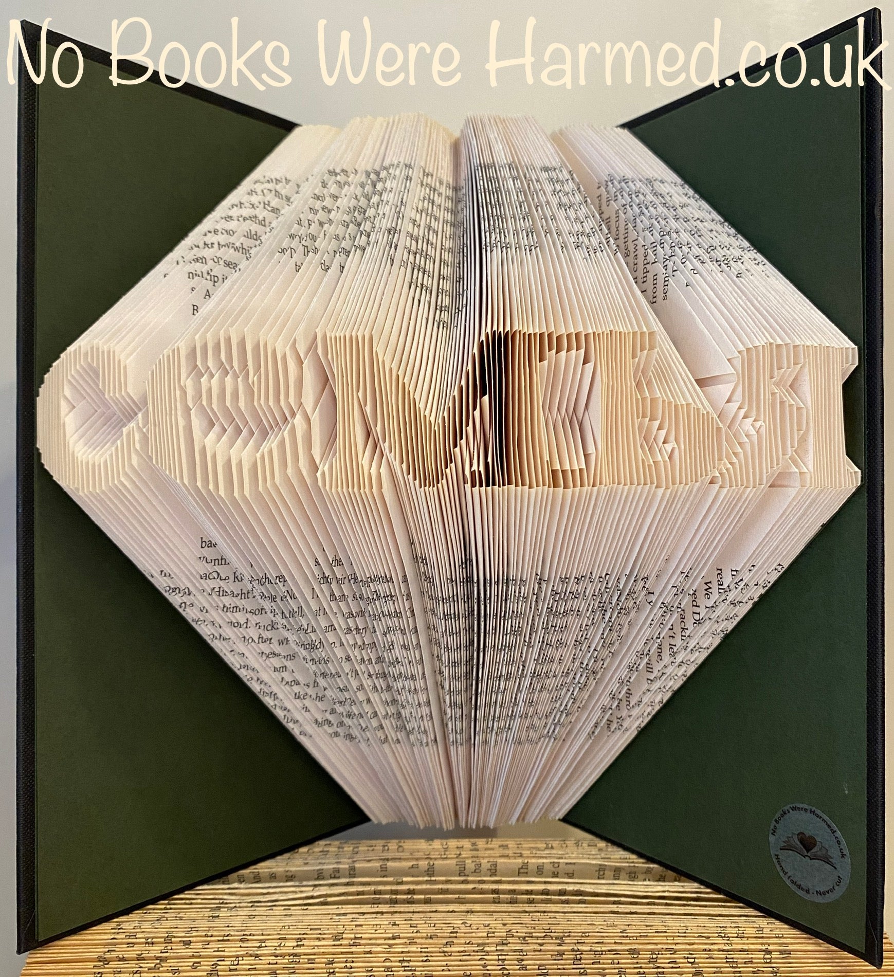 Hand-folded book art displaying the word 'семья' in Russian, crafted from vintage pages, showcasing unique textures and colors.