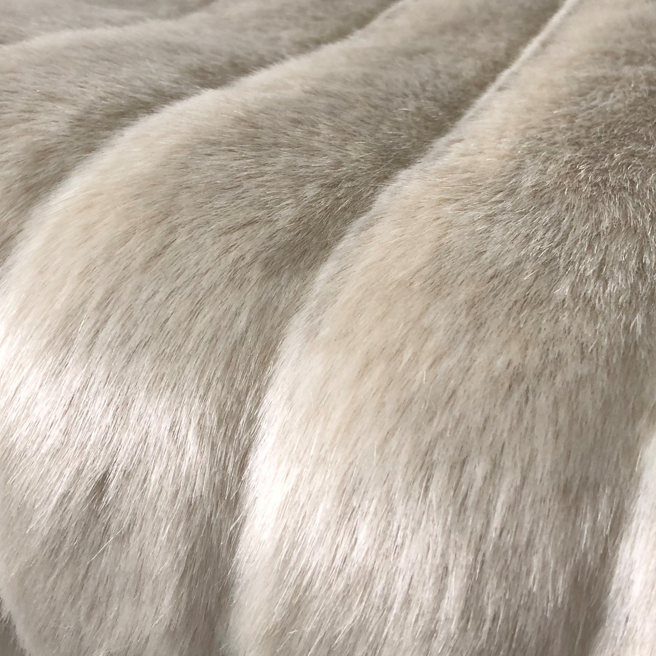Fancy Mink Faux Fur Ivory Luxury Throw blanket draped elegantly on a couch, showcasing its plush texture and elegant ivory color.