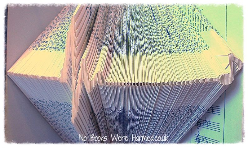 Art piece featuring a heart beat leading to a music note, crafted from hand-folded pages of vintage books.