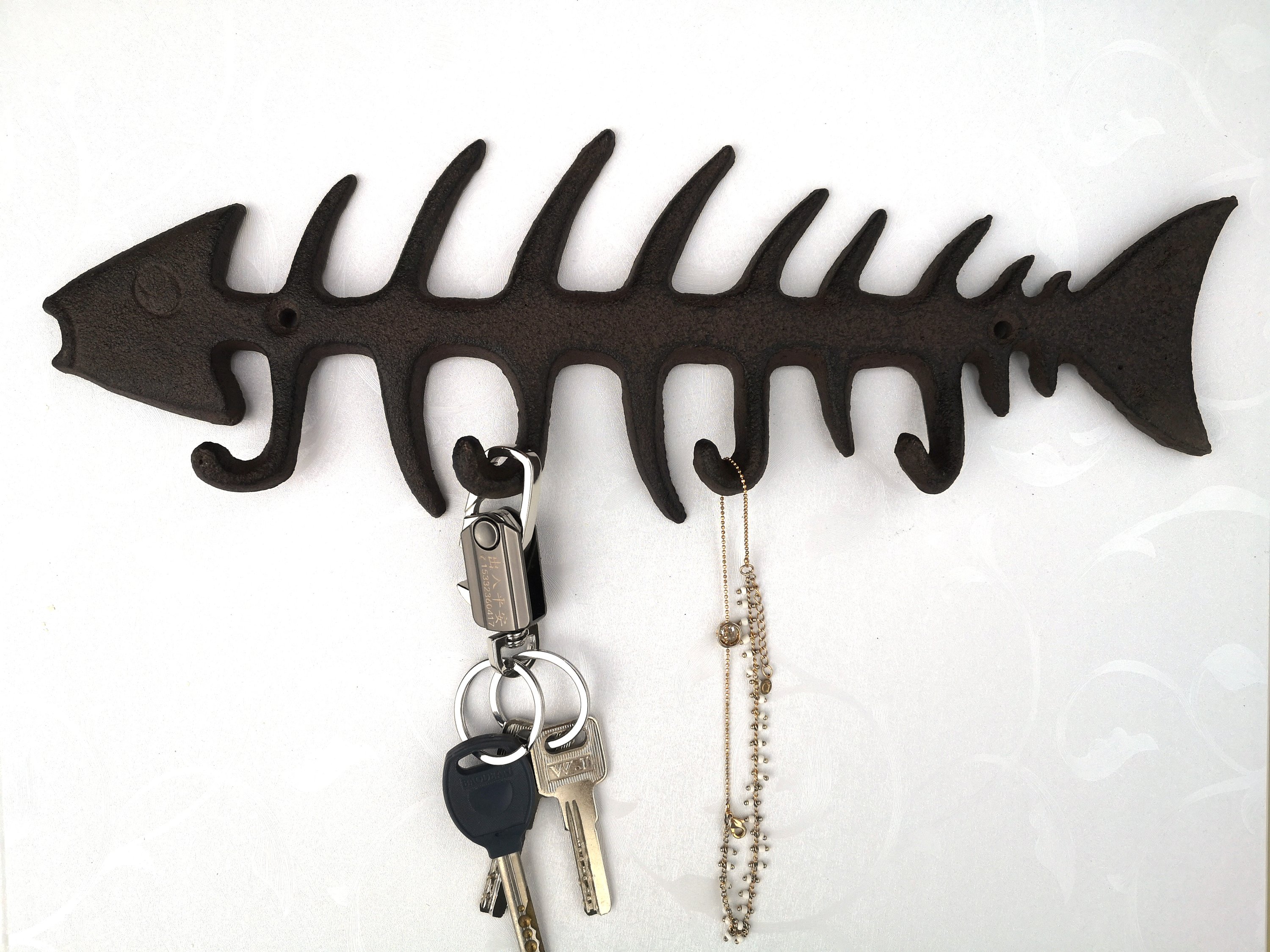 A set of unique fish bones wall hooks made of cast iron, featuring a rustic design with four hooks for hanging items.