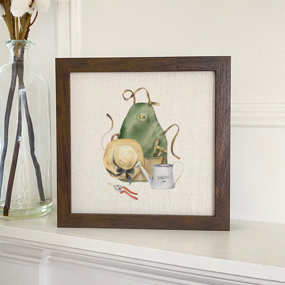 A beautifully framed sign featuring a garden apron and hat design, with a natural wood frame and eco-friendly printing on a linen-look background.