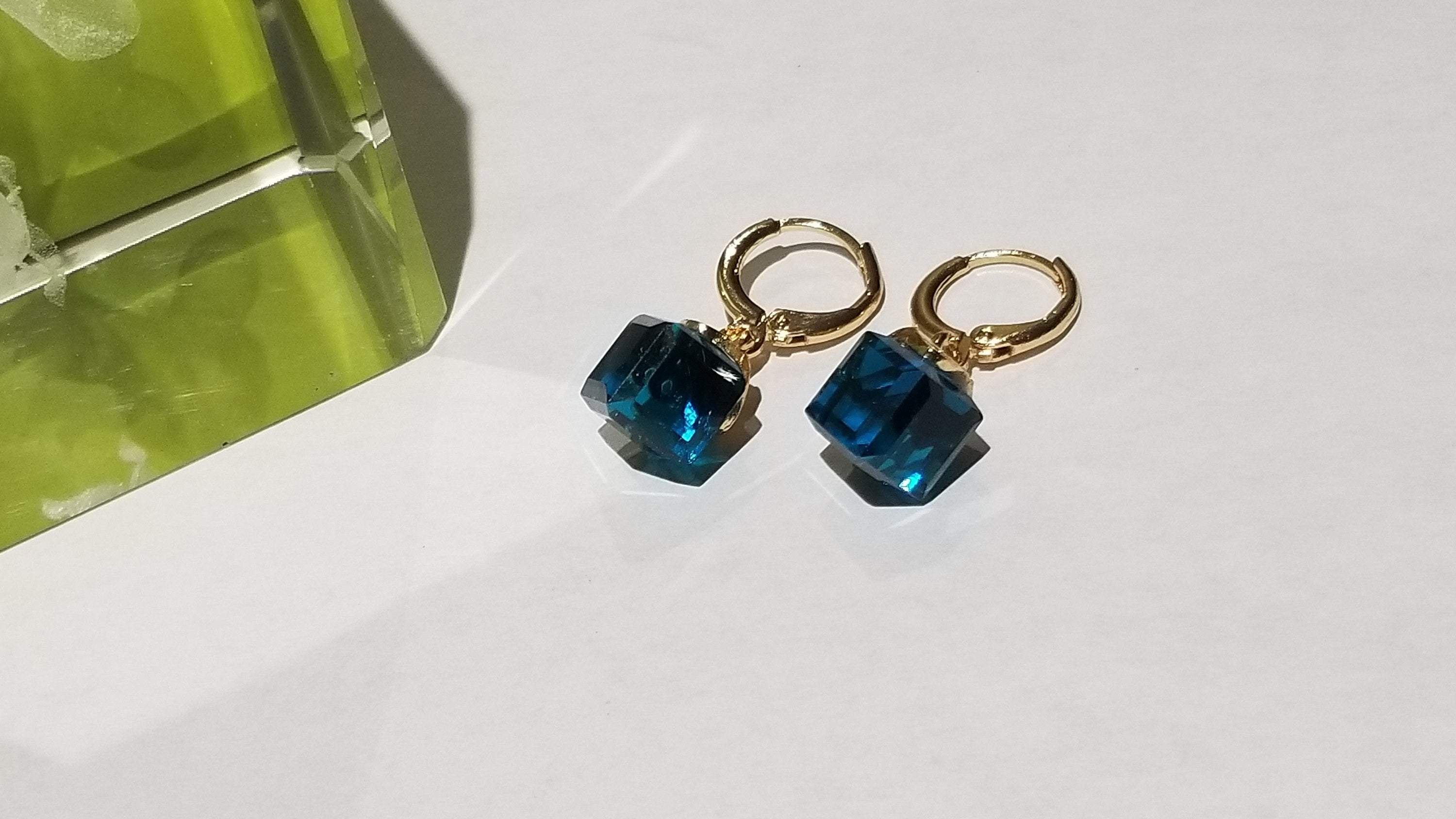 Stylish glass cube crystal earrings in blue, red, and peacock blue colors, showcasing their translucent design.