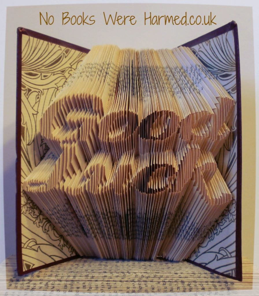 Hand-folded book art titled 'Good Luck', showcasing intricate designs from vintage books with unique colors and textures.