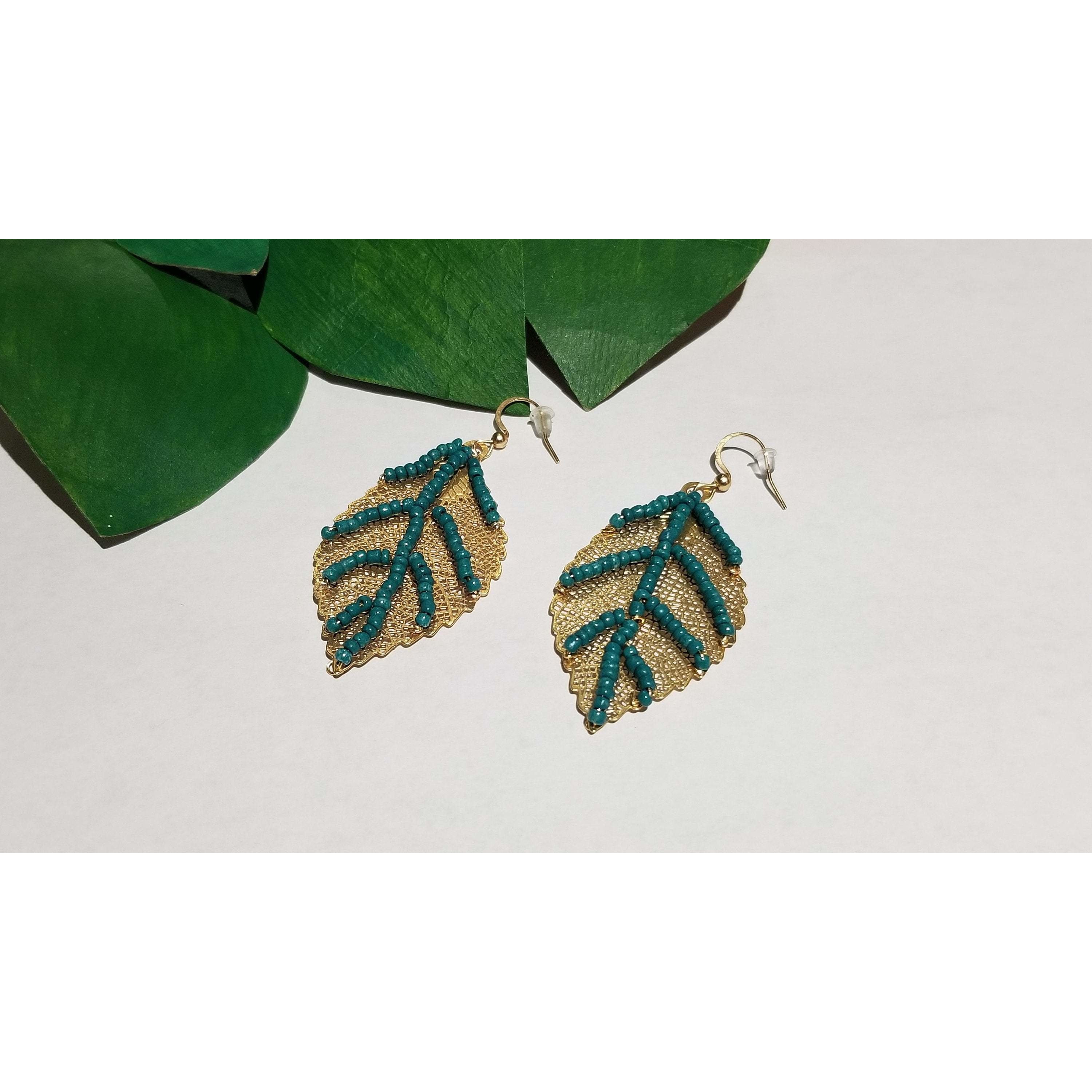 Golden leaf dangle earrings featuring green beaded veins, showcasing an elegant design perfect for nature lovers.