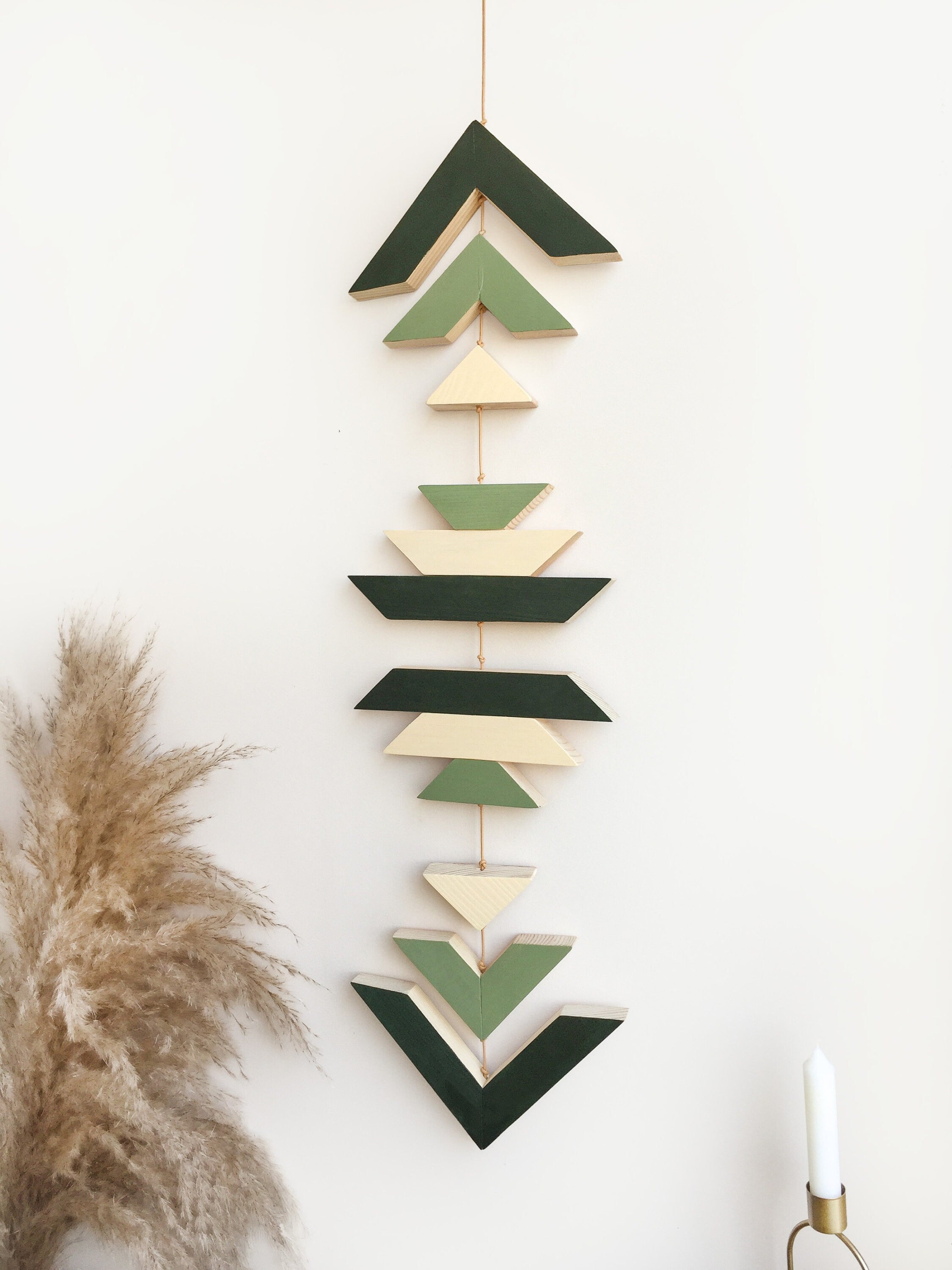 A beautiful geometric green wood wall hanging featuring sage green tones, connected with light brown cotton cord, perfect for boho decor.