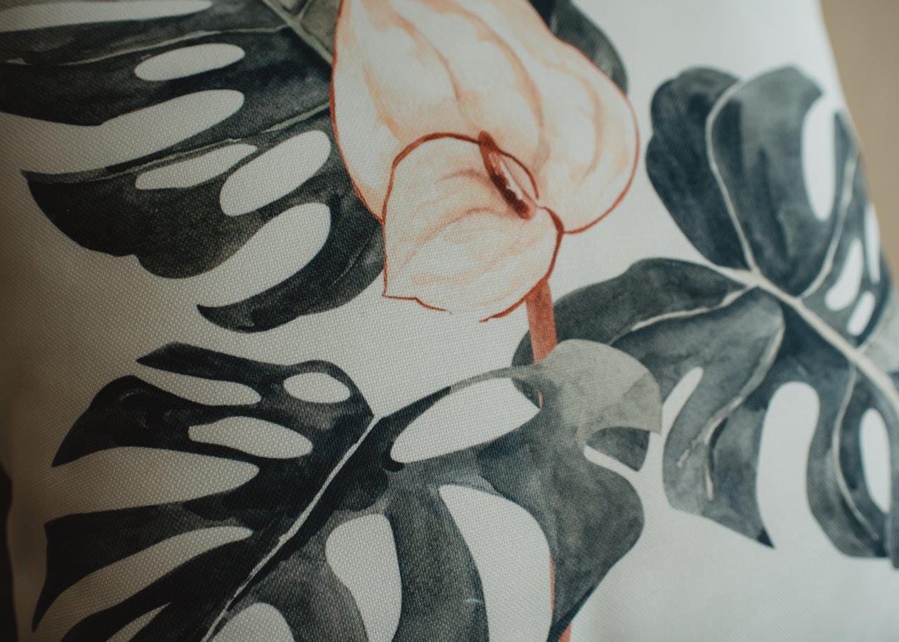 A modern mud-cloth pillow featuring a floral design with green leaves and soft pink flowers on a white background, showcasing a hidden zipper.