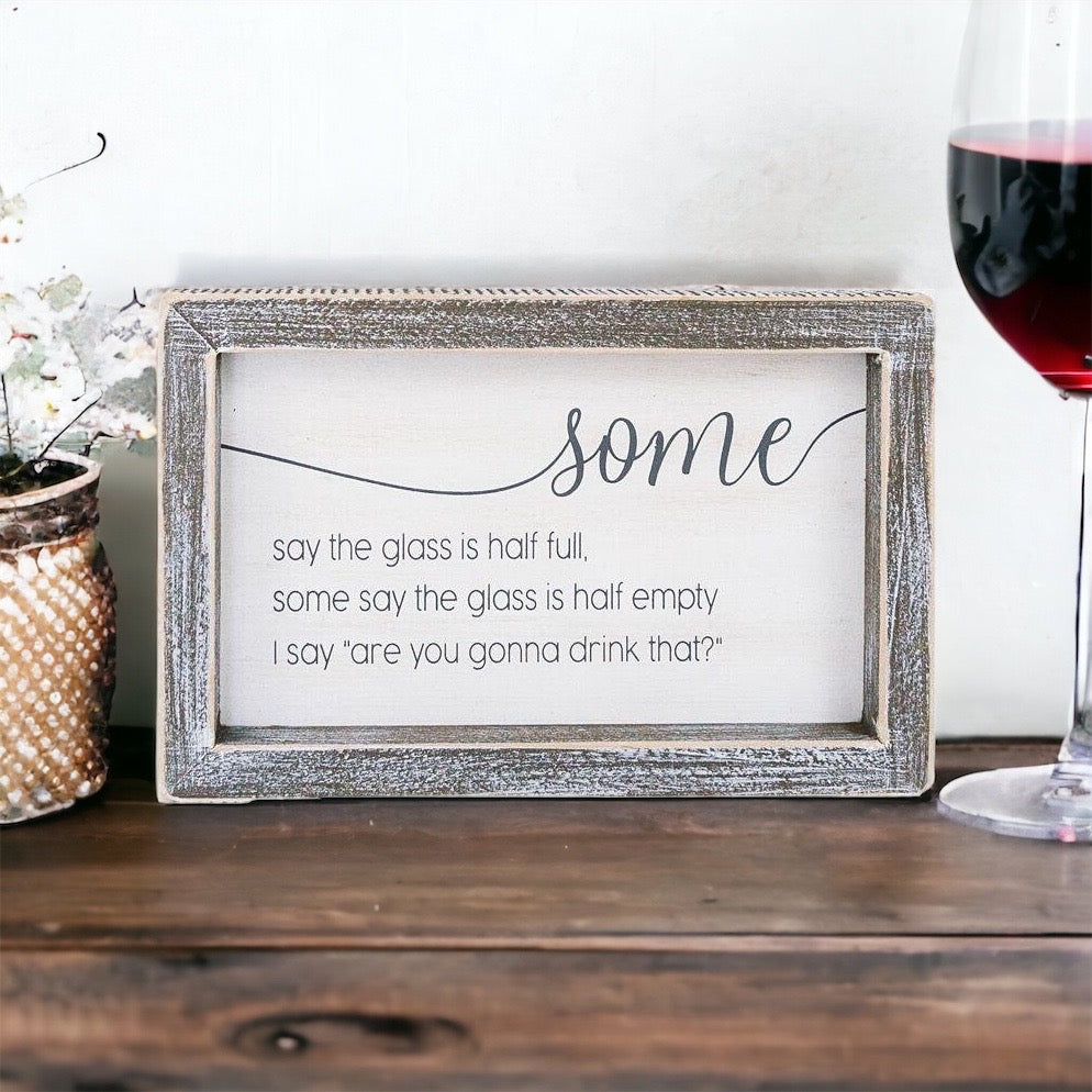 A wooden sign with the phrase 'Half Full or Empty' in white and grey colors, measuring 8 inches wide and 5 inches high.