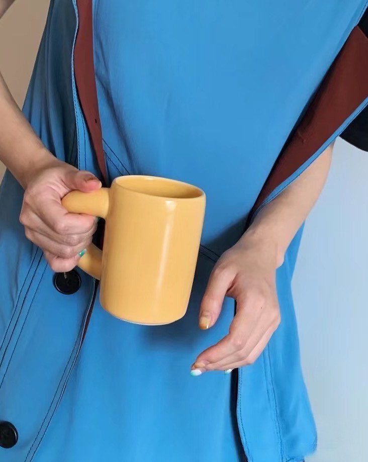 A set of handcrafted ceramic chubby mugs featuring a big twisted handle, available in silver, mango, and peach colors, perfect for coffee or tea.