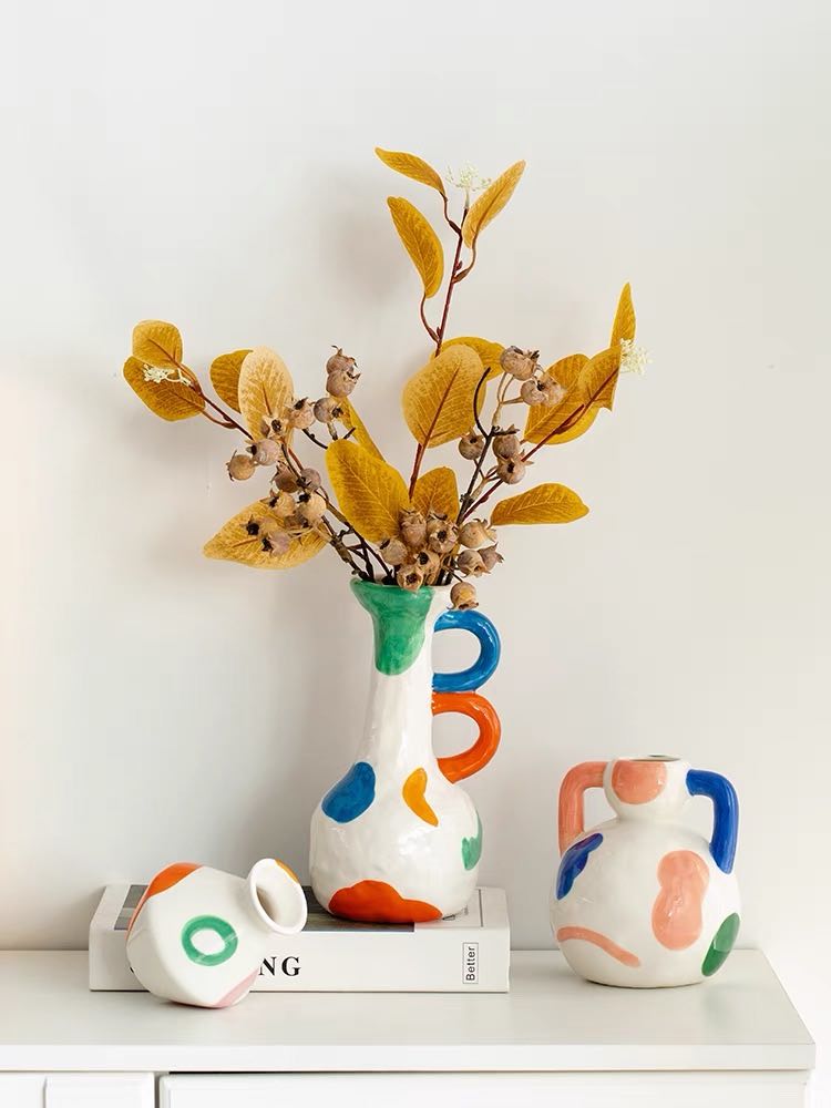 A colorful handpainted contemporary abstract ceramic vase featuring whimsical designs and vibrant colors, perfect for home decor.